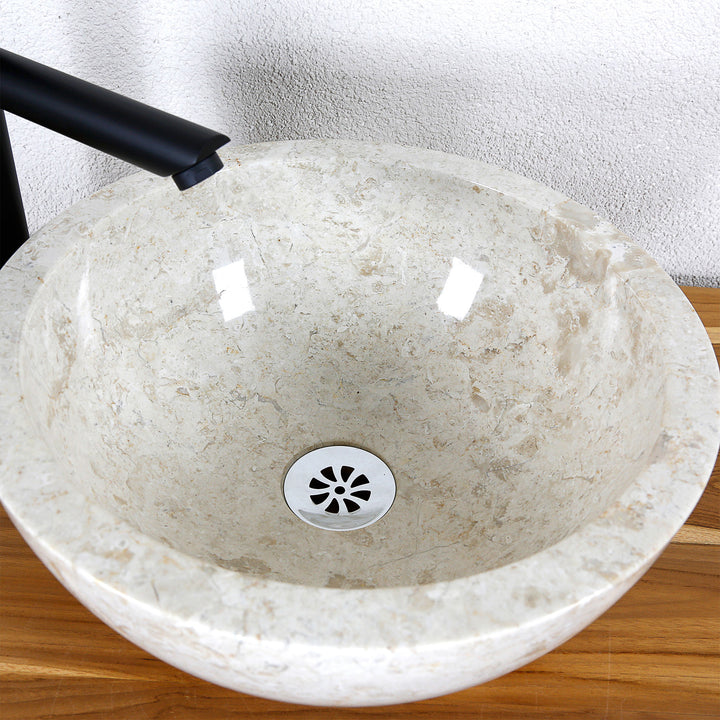 Gedetailleerde weergave van een ronde opzetwastafel van licht natuursteen met een gepolijst binnenoppervlak en centrale afvoer
