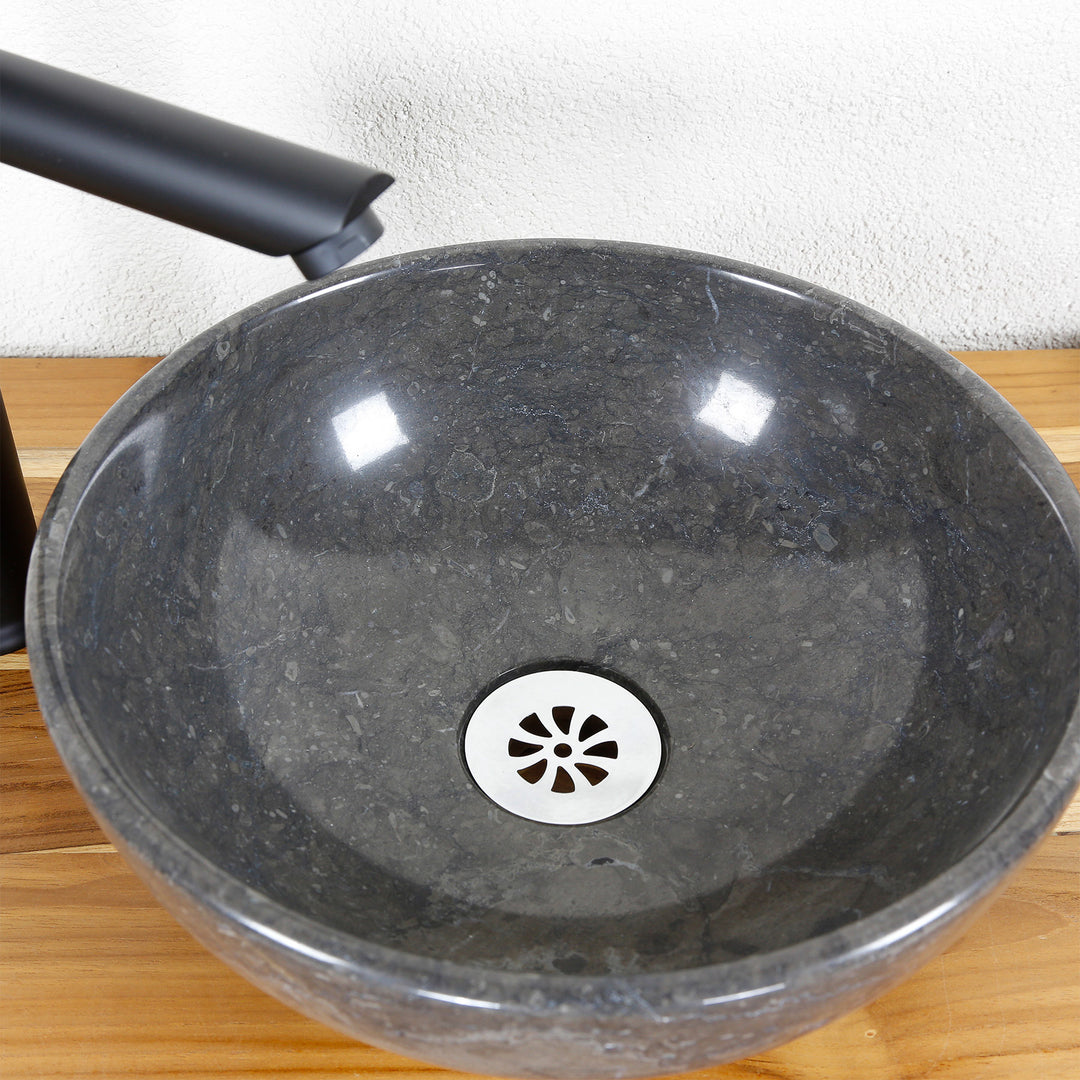 Ronde opzetwastafel van natuursteen in detail met gepolijst binnenoppervlak, RVS afvoer en armatuur