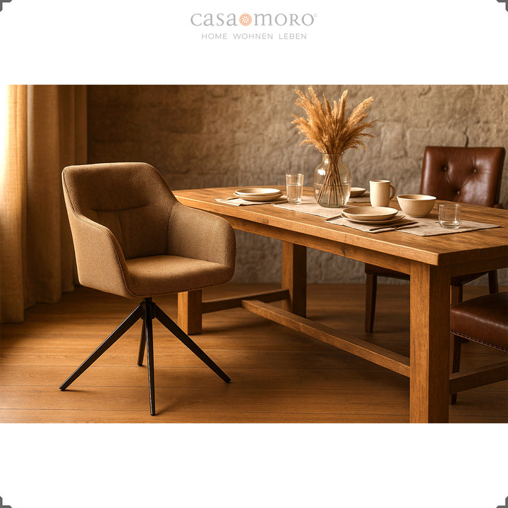 360° drehbarer Polsterstuhl mit Armlehnen in Braun an einem Holztisch mit Natursteinwand, gedecktem Tisch und warmem Lichteinfall