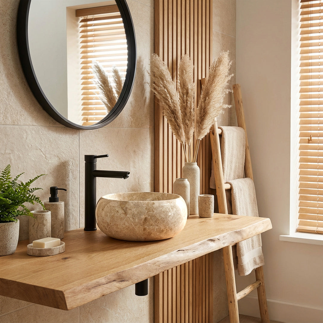 Ronde opzetwastafel van licht natuursteen op houten wastafel met zwarte armaturen in een lichte, moderne badkamersfeer