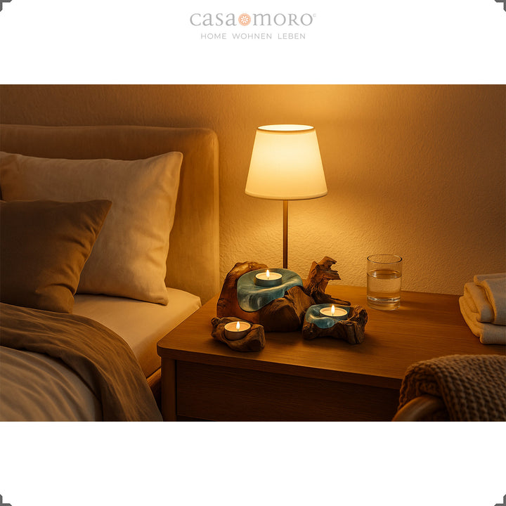 Drei Teelichthalter aus Glas und Wurzelholz auf einem Nachttisch, deren sanftes Kerzenlicht eine beruhigende Schlafzimmerstimmung schafft.